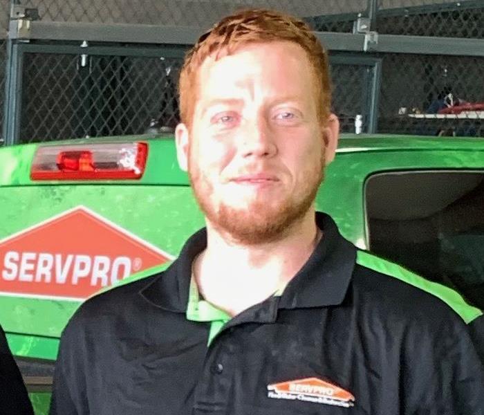 a smiling SERVPRO employee against a truck in the background