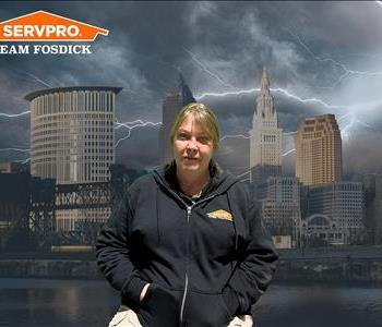 Blonde woman in a black zip up sweatshirt in front of a stormy Cleveland background